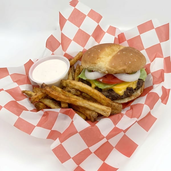 Cheeseburger with lettuce, tomato, onion, and fries with dipping sauce in a red checkered basket.