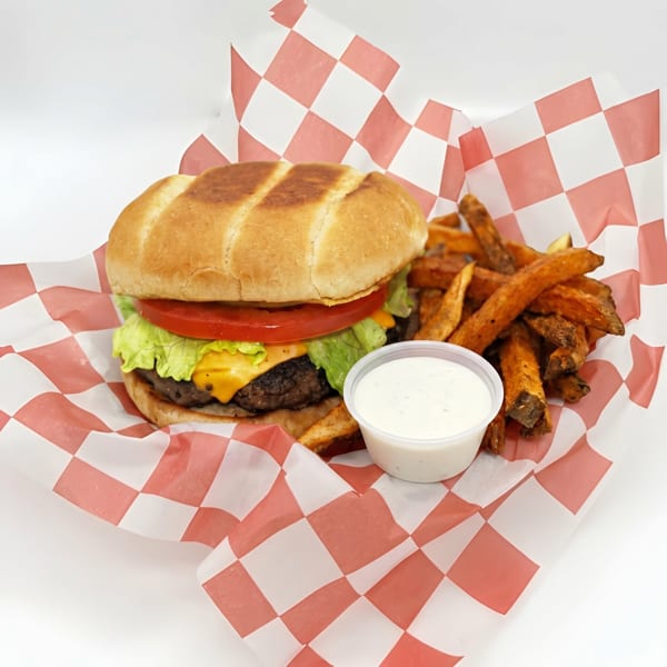 Cheeseburger with lettuce, tomato, and a side of sweet potato fries and dipping sauce.