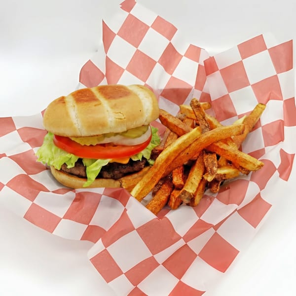 Cheeseburger with lettuce, tomato, onion, and pickles, served with fries in a red and white checkered basket.