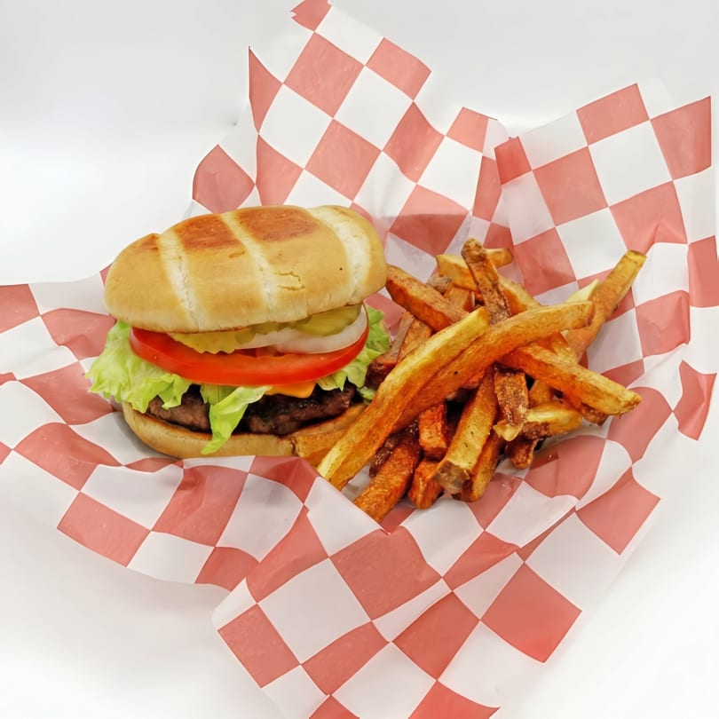 Cheeseburger with lettuce, tomato, onion, and pickles, served with fries in a red and white checkered basket.