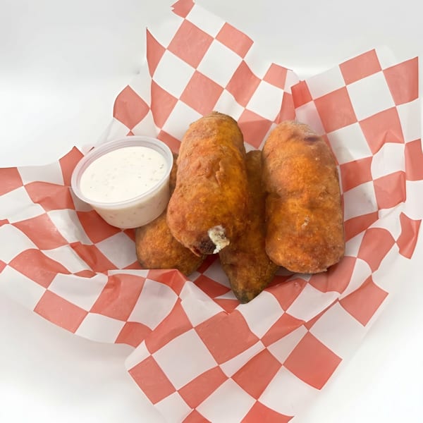 Deep-fried golden brown appetizers with a side of white dipping sauce in a red and white checkered basket.